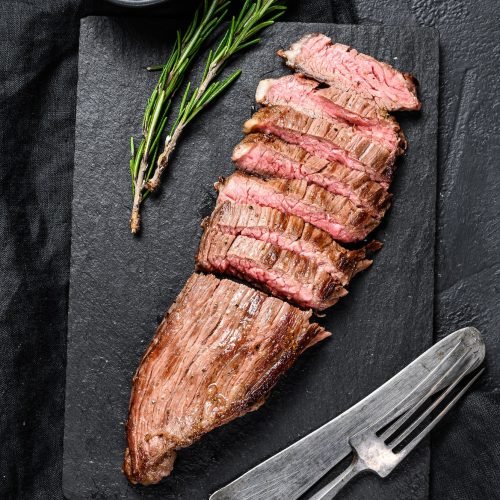 grill-restaurant-beef-menu-flank-steak-on-a-black-stone-board-black-background-top-view.jpg